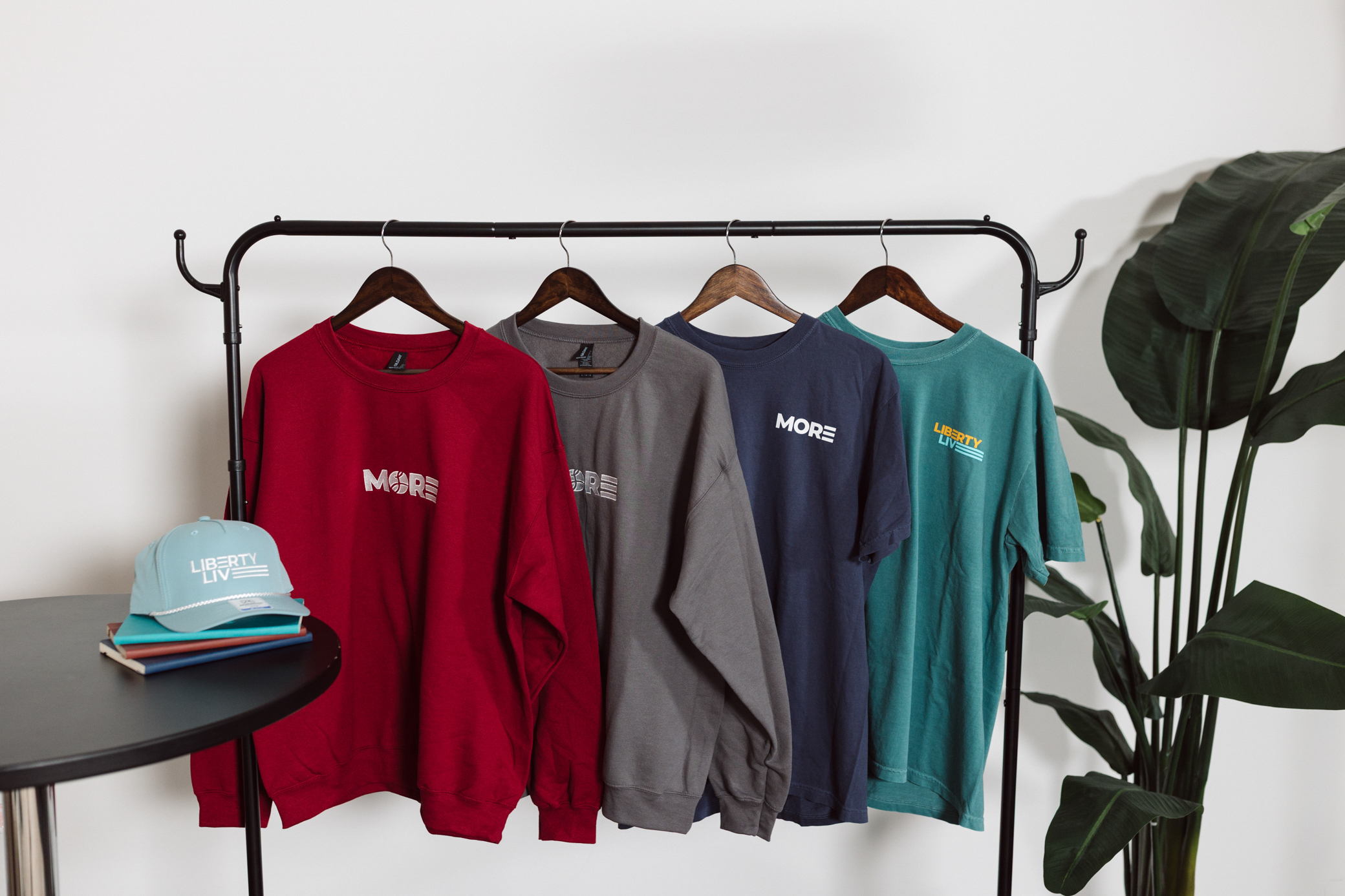 MORE crewnecks, tees and hat hanging on a clothing rack